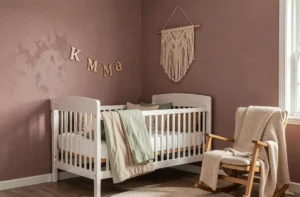 Chambre de bébé moderne et cosy avec berceau en bois blanc, literie en coton bio vert sauge, suspension macramé et lettres décoratives en bois